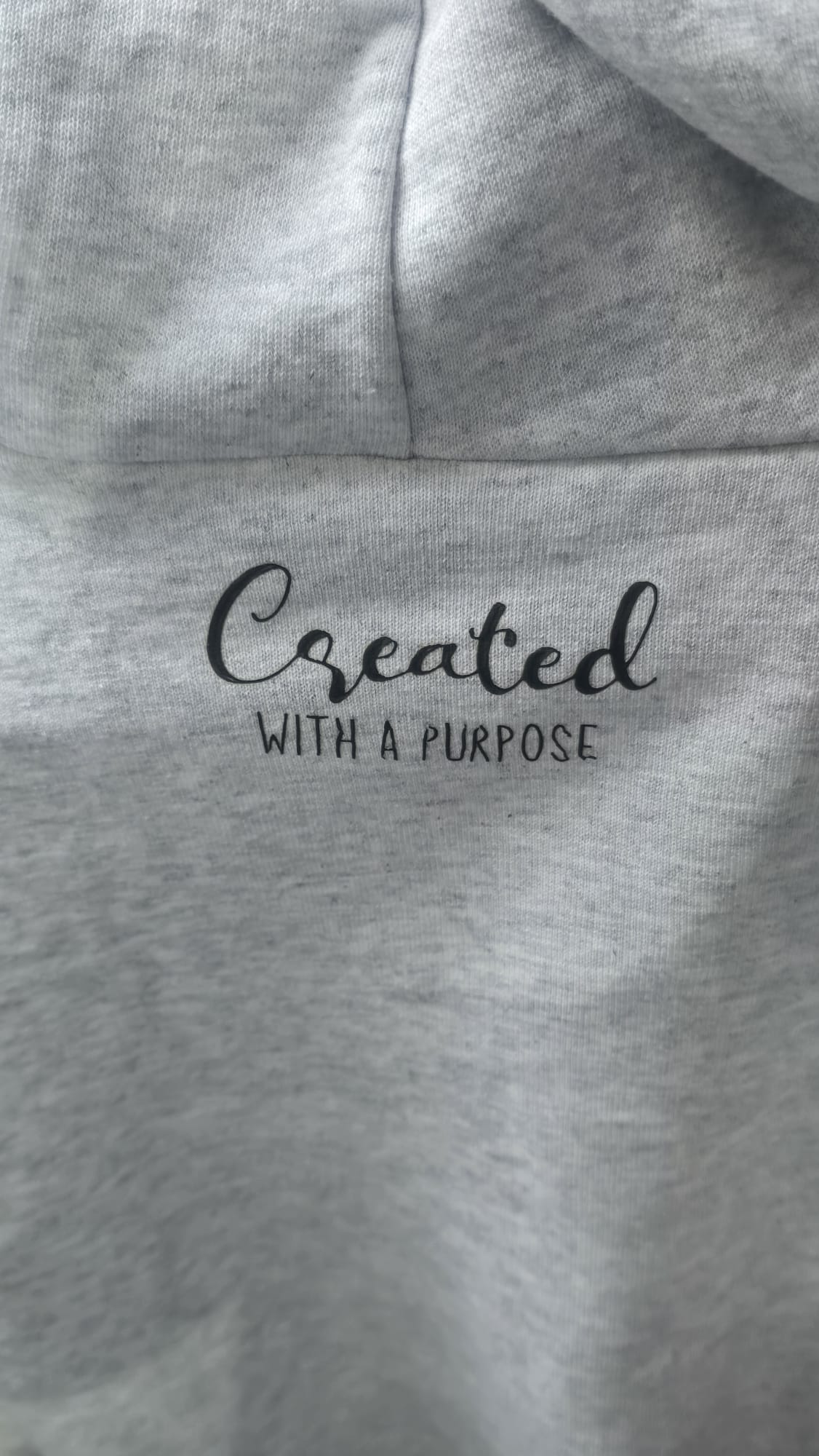 Close-up of Created With A Purpose script print on back of grey hoodie