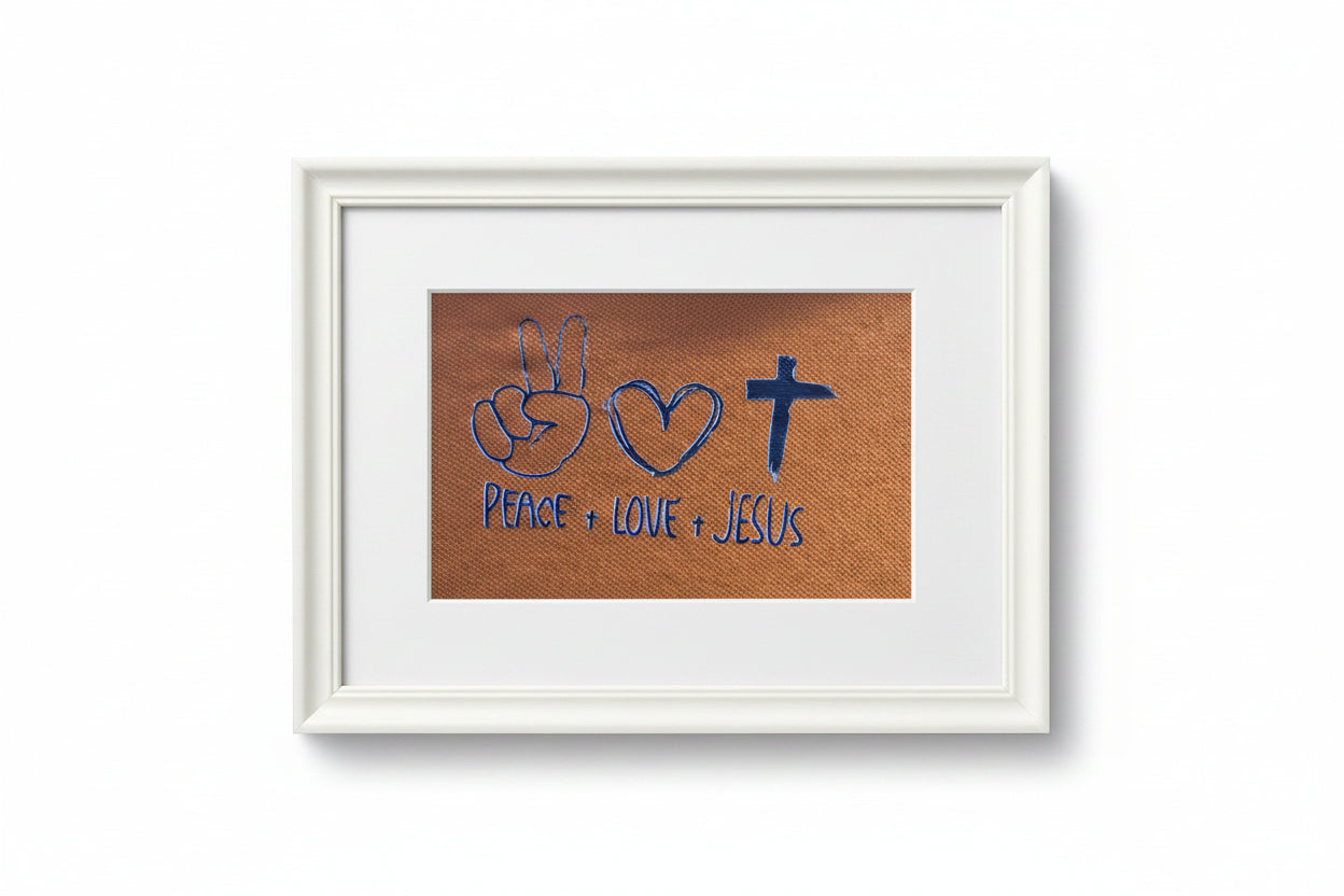 Close-up of a brown woven fabric with blue embroidered symbols and text reading 'PEACE + LOVE + JESUS' beneath a peace sign, heart, and cross.