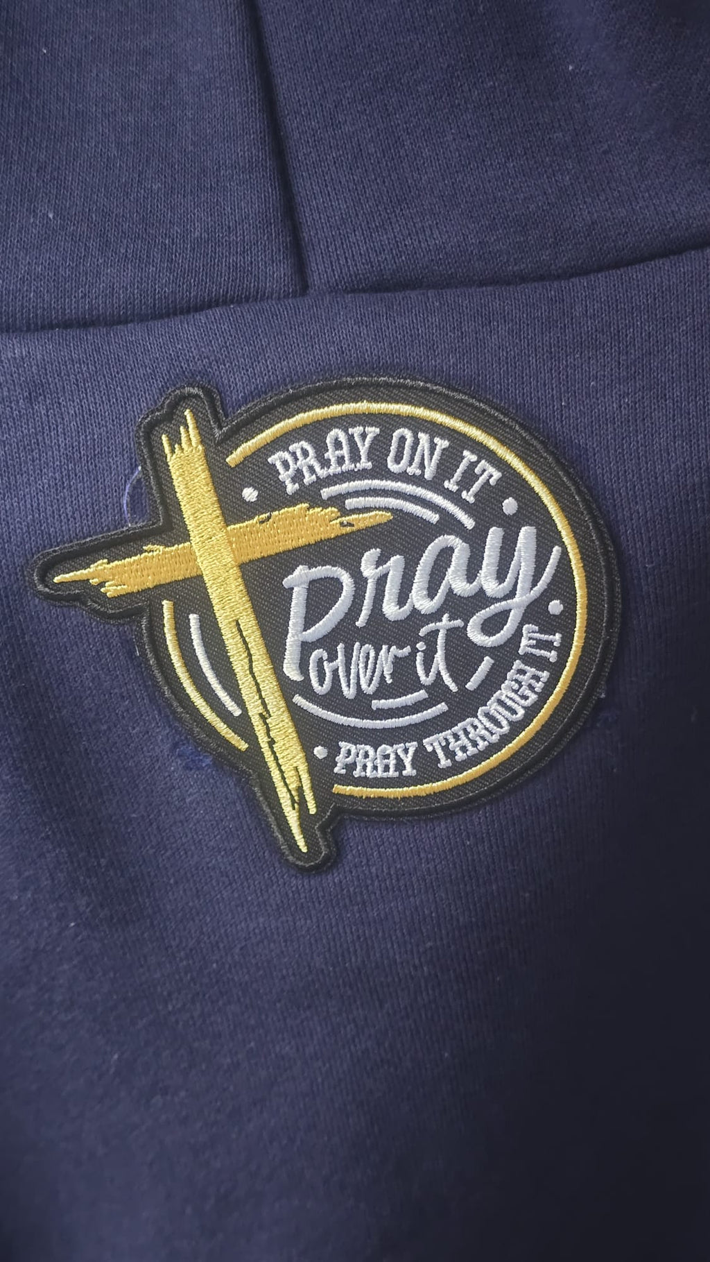 Close-up of Pray On It Pray Over It Pray Through It embroidered patch on navy hoodie