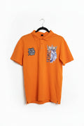 An orange short-sleeve polo shirt hanging on a black hanger, featuring a graphic print of a lion and crown on the left chest and a logo on the right sleeve.